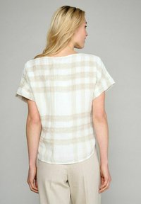 Beige og hvid kortærmet bluse med et tekstureret stribet mønster, der har en afrundet kant og en afslappet pasform.