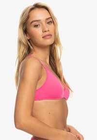 Roze bikini-top met driehoekige cups, dunne verstelbare bandjes en een gladde textuur. Eenvoudig ontwerp geschikt voor zwemkleding.