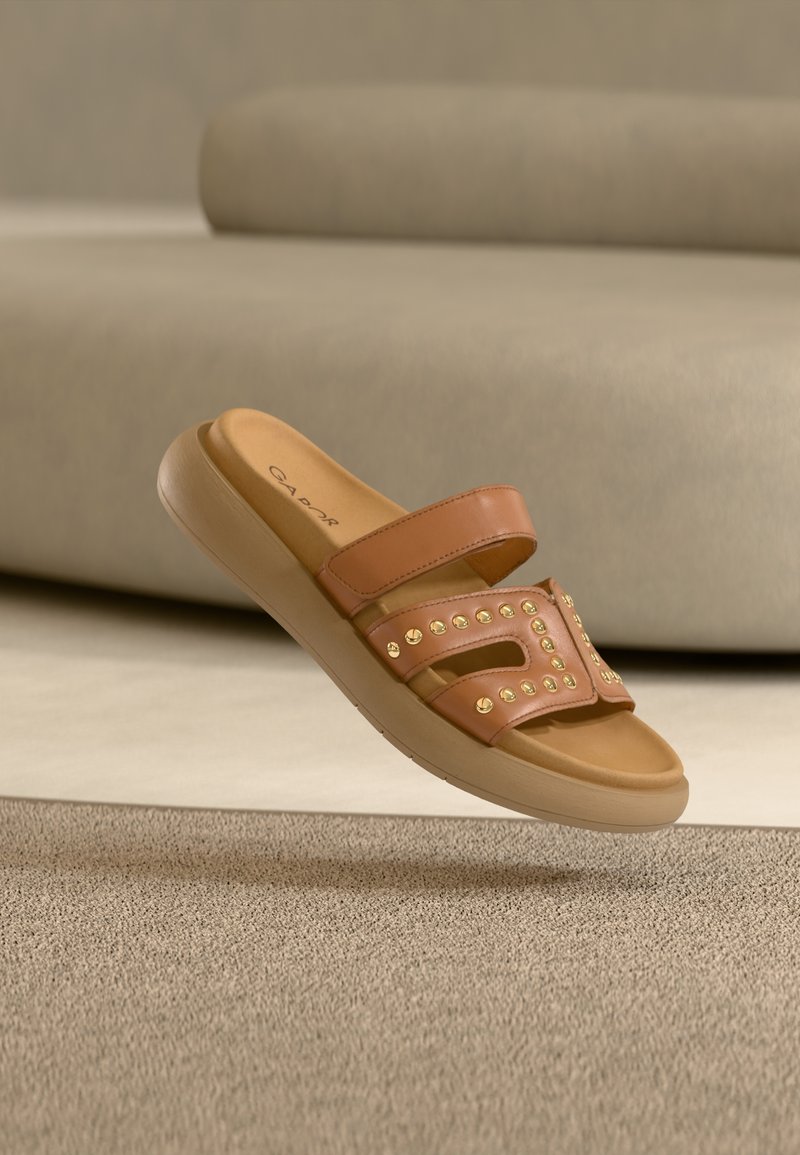Καφέ σανδάλι χωρίς λουράκια με δύο λωρίδες, διακοσμητικά τρουκς και μαξιλαρωτή μπεζ σόλα· λεία υφή με ανοιχτό σχέδιο και ανοίγματα.