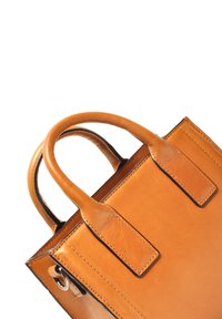 Tan leren handtas met dubbele ronde handvatten, gladde textuur, minimalistisch ontwerp en gestikte randen. Bevat kleine metalen hardwareaccenten.