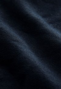 Marineblåt stof med en glat tekstur, der har subtile lyse refleksioner og blide bølger, hvilket indikerer dets fald og følelse.