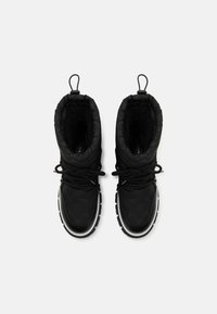 Bottes imperméables noires avec une texture matelassée, des semelles en caoutchouc et un système de laçage intégré. Présentant un motif distinctif à l'extérieur.