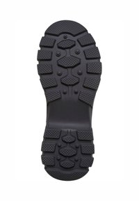 Suela de zapato de goma negra con un patrón de banda de rodadura robusto, que presenta tacos de diversas formas para ofrecer agarre; sección central suave para mayor flexibilidad.