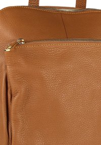 Bruine leren tas met een textuur, uitgerust met een horizontale ritszak met een gouden rits en een bijpassende leren trekstrip.