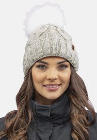 Cappello di lana grigio chiaro, con un grande pompon bianco soffice sulla parte superiore, caratterizzato da un design a coste testurizzato e un piccolo tag in pelle marrone.