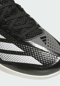 Black athletic shoe with a mesh upper, featuring shiny black and white accents, textured patterns, and a white sole.
