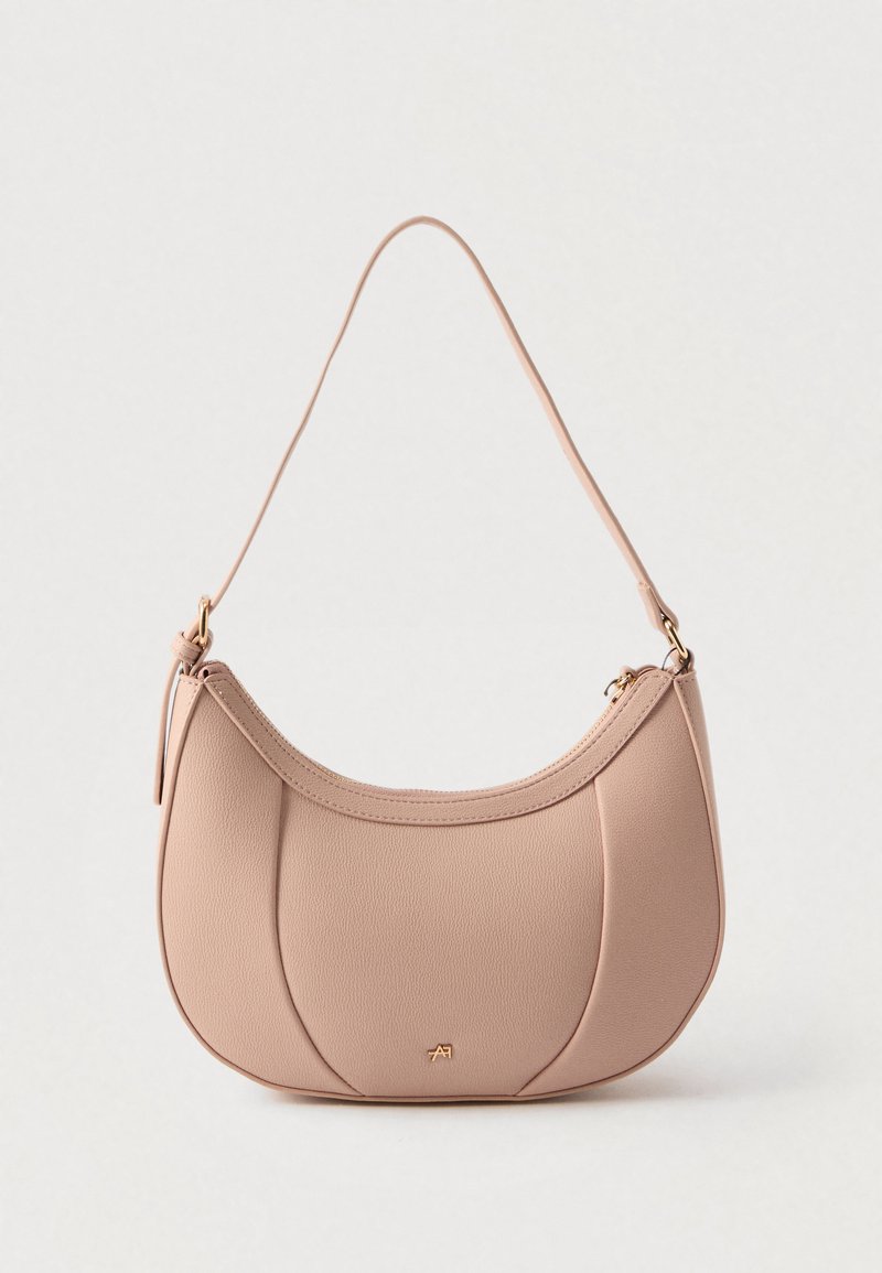 Sac à main en cuir beige en forme de croissant avec une bandoulière unique, une fermeture éclair dorée et un petit logo doré sur le panneau central avant.