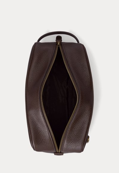 Trousse de toilette en cuir marron texturé avec fermeture éclair dorée ouverte montrant un intérieur sombre et vide, vue de dessus sur fond blanc.
