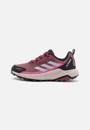Bordowo-różowy but do biegania trailowego Adidas Terrex z białymi paskami, czarną podeszwą i napisem „Rain.RDY” na czubku buta.