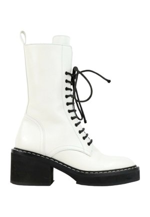 White mid-calf leather boot with black chunky heel and sole, black laces tied in a bow, and pull tab at the back.