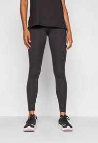 Svarta sportleggings i elastiskt tyg, med en åtsittande design och en jämn yta. Kombineras med svarta sneakers.