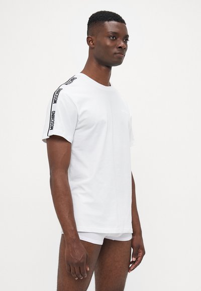Vit bomull t-shirt med kort ärm, med en svart logotyp på axeln och en avslappnad passform. Snygg textur och enkel design.