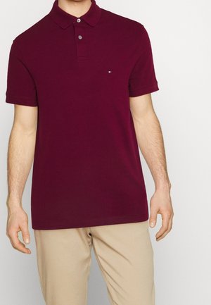 Bordeauxrød kortærmet polo med klassisk krave, med to knapper og et lille logo på venstre bryst. Bomuldsstof med glat tekstur.