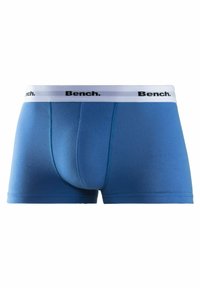 Blue boxer briefs made from stretchy fabric. Features a white elastic waistband with "Bench." logo in black. Smooth texture and mid-length style.