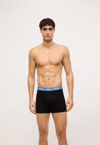 Boxer shorts neri con una vita blu brandizzata "HUGO", realizzati in un tessuto morbido, caratterizzati da un design fitted e una texture liscia.