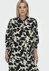 Langærmet, knap-op skjorte i en cremefarvet bund med store sorte abstrakte pletter, med en klassisk krave og afslappet pasform. Blødt stof. 