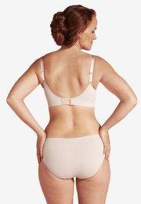 Beige bh och trosor-set med sömlös design, justerbara axelband och krok-och-öga stängning, som framhäver en mjuk textur.