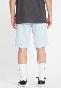 Light blue shorts made of smooth fabric, straight cut, finished with a hem. Worn with black shoes and white ribbed socks with logo.
