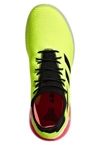 Kengät urheilun neon keltaisella värillä, mustilla nauhoilla ja neulotulla kielillä, mustilla sivuviivoilla, punaisella sisäpohjalla sekä punaisella ja valkoisella pohjalla.