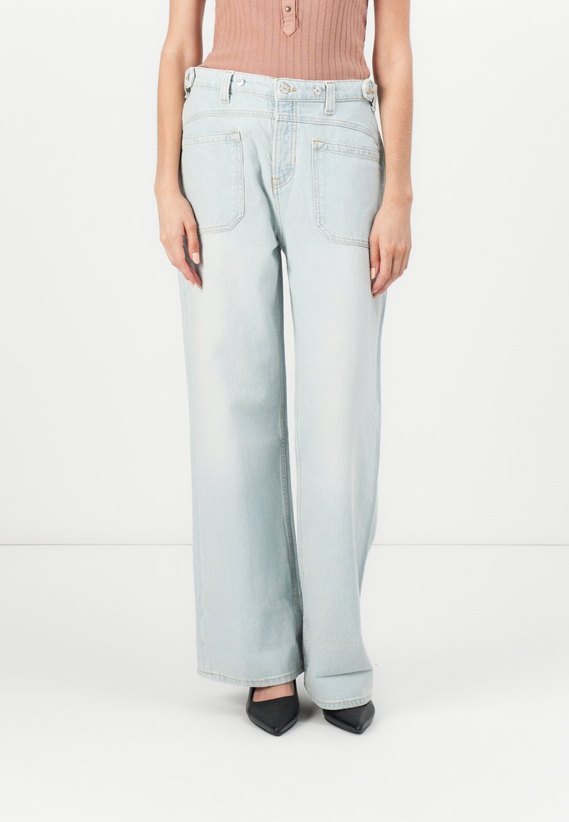 Lichtblauwe wijde jeans van denim, met een hoge taille, twee achterzakken en een licht vervaagde afwerking. Gecombineerd met zwarte hakken.