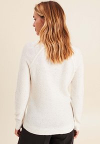 Weißer Strickpullover mit Sprenkeln, langen Ärmeln, runder Ausschnitt, geripptem Saum und Rückendetail. Weicher, texturierter Stoff mit lockerer Passform.