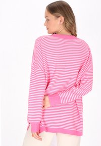 Růžový a bílý pruhovaný oversized svetr s žebrovanými manžetami a výstřihem, který se vyznačuje volným střihem a bočními rozparky na lemu.