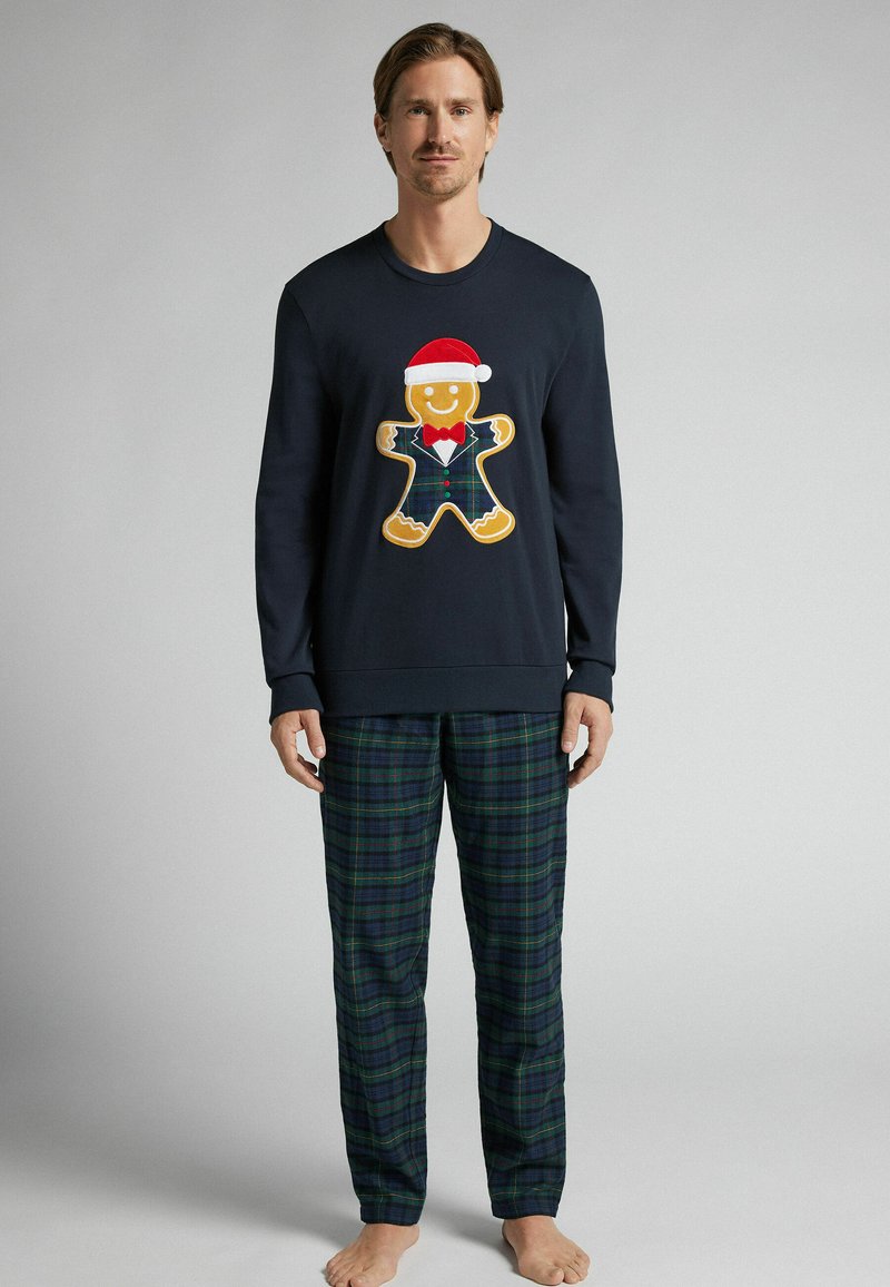 Námořnická mikina má grafiku perníkového muže se santovskou čepicí; kostkované pyžamové kalhoty v zelených a modrých odstínech; casual, měkká tkanina.