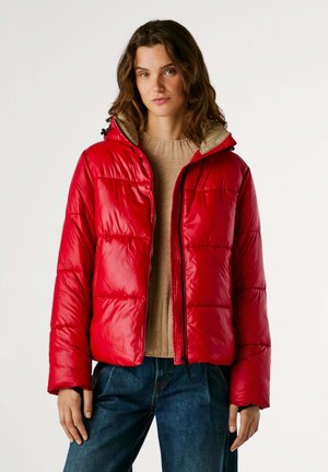 Giacca rossa gonfiabile con apertura frontale con zip, vestibilità oversize, polsini elasticizzati e fodera interna beige. Texture liscia e lucida con trapuntatura visibile.