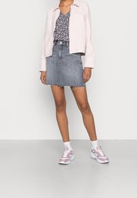 Veste courte rose pâle, haut fleuri bleu marine, mini-jupe en jean gris à ourlet effiloché, chaussettes blanches, baskets roses et blanches.