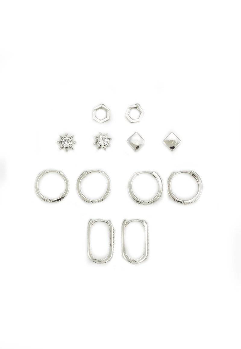 Ensemble de boucles d'oreilles en argent présentant différentes formes : anneaux, hexagones, diamants et designs de soleil, certains ornés de cristaux transparents, texture lisse.