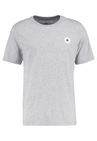 Camiseta gris de manga corta hecha de tejido suave. Presenta un escote redondo y un logo circular con una estrella azul en el lado izquierdo del pecho.
