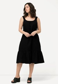 Schwarzes ärmelloses Kleid mit gerafftem Ausschnitt und fließendem Saum. Hergestellt aus weichem Stoff, mit breiten Trägern und lockerer Passform.