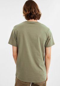 Oliven grøn bomulds t-shirt med rund halsudskæring og korte ærmer. Blød tekstur, lige snit og enkelt design. Ingen synlige mønstre eller udsmykninger.