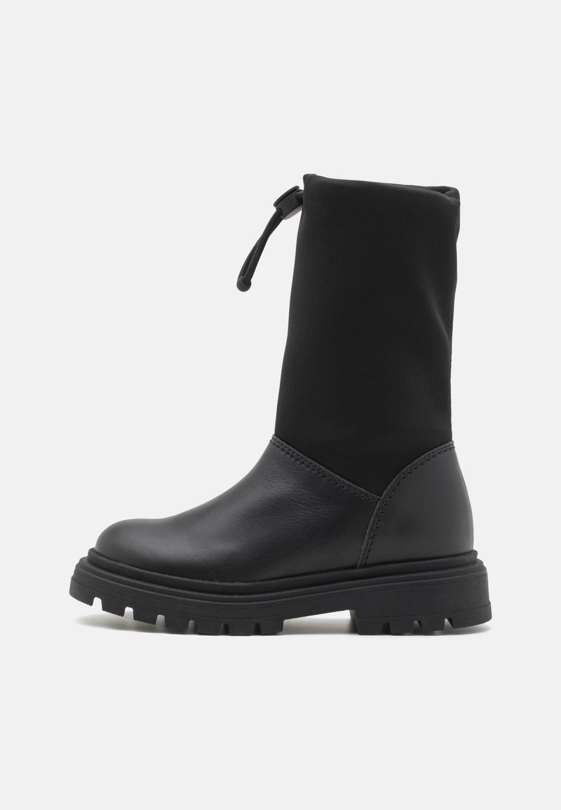 Svart ankelboot med en strukturerad läderfot och en överdel i tyg. Den har en rund tå, texturerad sula och justerbar drarem.