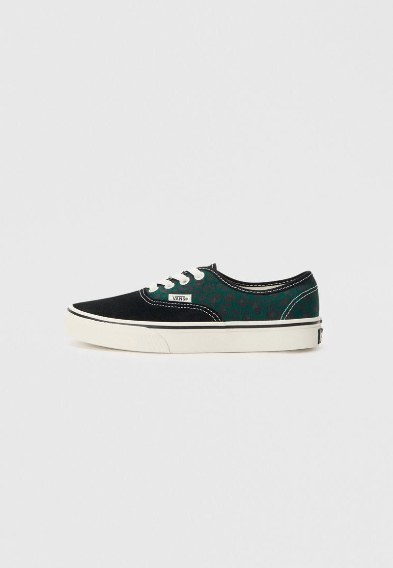 Svarta canvas sneakers med gröna leopardmönstrade detaljer, vita snören och en gummisula. Har kontrasterande sömmar och en märkeslogotyp.