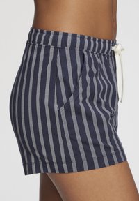 Navy blue cotton shorts with white vertical stripes, featuring side pockets and an elastic waistband with a drawstring.