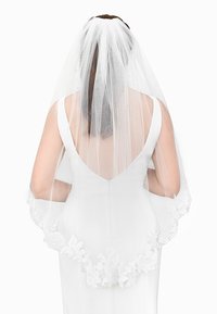 Trouwjurk met een diepe rug, voorzien van een doorzichtige witte sluier versierd met bloemenkantaccenten langs de randen.