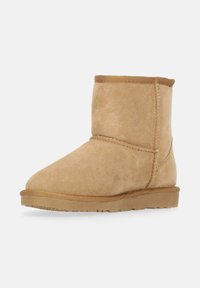 Beige Wildleder-Stiefelette mit runder Zehenpartie, sichtbaren Nähten und einer flachen Gummisohle. Verfügt über eine weiche Textur und ein nahtloses Design.