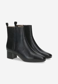 Bottines noires en cuir avec un bout pointu, un petit talon carré et des languettes de tirage. Texture lisse et design minimaliste.