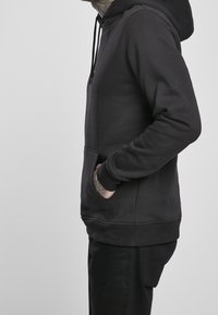 Schwarzer Pullover mit Kapuze, Seitentaschen, gerippten Bündchen und Saum. Hergestellt aus glattem Stoff, mit lässiger Passform und minimalistischem Design.