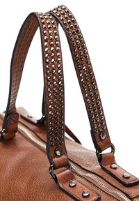 Borsa in pelle marrone con cinturini marroni borchiati, hardware argentato e finitura texturizzata. Presenta una chiusura con zip superiore e contrasti nei dettagli.