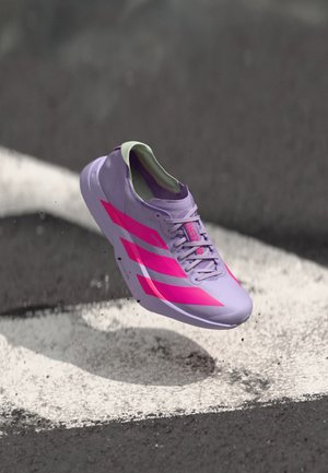 Chaussure de course violet clair avec des rayures et des accents roses, dotée d'un design élégant, d'une tige texturée et d'un col rembourré. Flottant au-dessus d'une surface.