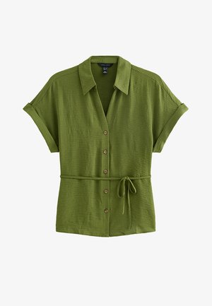 Blouse verte olive à manches courtes, boutonnée, avec col et ceinture en tissu nouée à la taille, matière légère texturée.