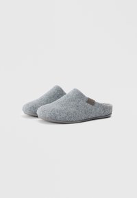 Chinelos de feltro de lã cinza com uma forma suave e arredondada, apresentando um interior macio e uma sola de borracha texturizada. Logótipo da marca castanho na lateral.