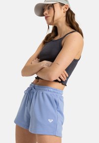 Lichtblauwe katoenen shorts met elastische tailleband en trekkoord, voorzien van zijzakken en een klein wit hartlogo op het linkerpand.