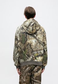 Hooded sweatshirt featuring a camouflaged print resembling bark and foliage, with ribbed cuffs and hem, in earthy tones of brown and green.