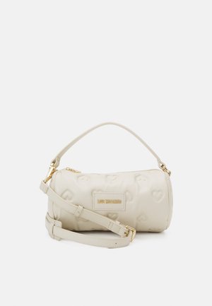 Bolso cilíndrico de color crema hecho de cuero texturizado con patrones de corazones en relieve. Cuenta con una correa desmontable y detalles en metal dorado.