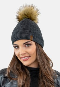 Gebreide zwarte beanie met een nep bont pompon bovenop, voorzien van een gestructureerd ontwerp en een klein leren logo-label aan de zijkant.