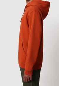 Oranžová mikina s kapucí, klokaní kapsou, šňůrkou na stažení kapuce, žebrovanými manžetami a lemem. Vyrobena z měkkého materiálu pro pohodlí.