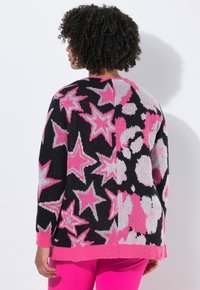 Schwarzer Strickpullover mit rosa und weißen Stern- und Blumenmustern. Verfügt über rosa gerippte Bündchen und Saum, lockere Passform und weiche Textur.